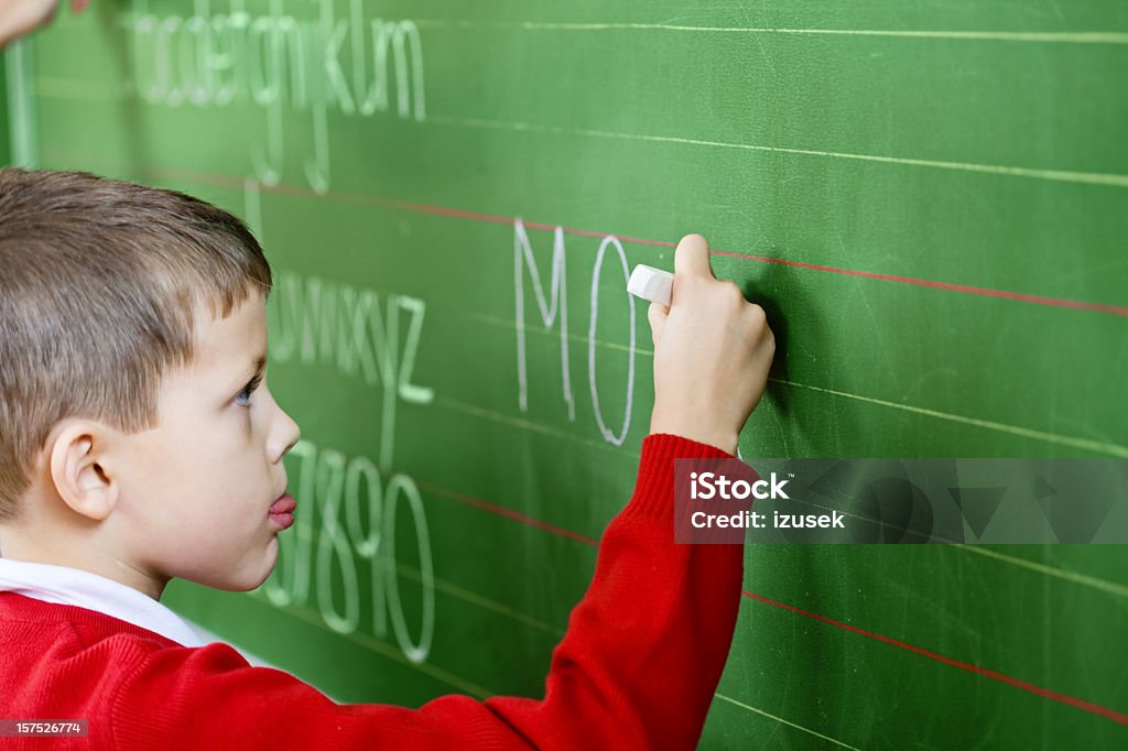 School Boy Writing On Blackboard, Side View  Boys Stock Photo