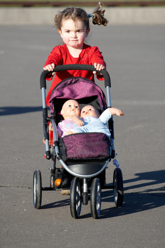 Little girl pushing her dolls pram