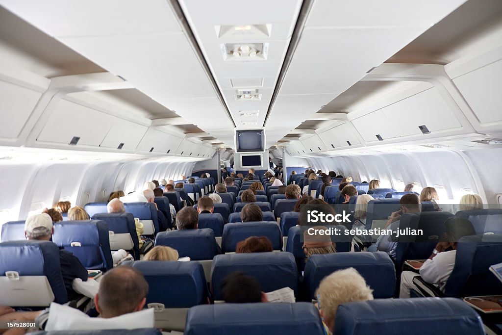 The interior of an airplane with passengers inside of an airplane with large group of people - long exposure - soft focus - camera canon 5D mark II - unsharped RAW - adobe colorspace Airplane Stock Photo