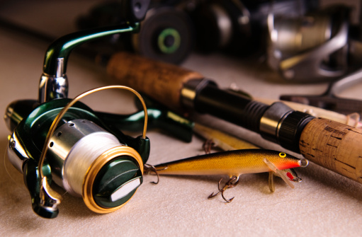 Still life shot of fishing bait, reels and a fishing rod.