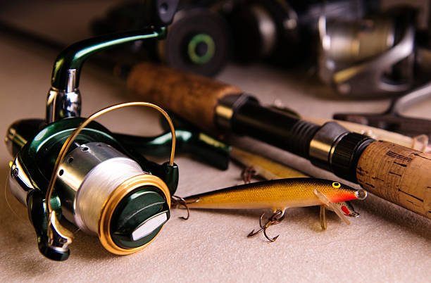 Close-up of different fishing tackle Still life shot of fishing bait, reels and a fishing rod. hook equipment stock pictures, royalty-free photos & images