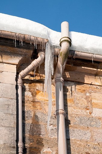 Snow and ice causing problems with gutters and drains on an old building.