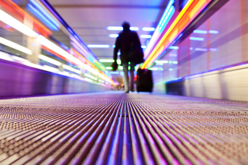 Man walks down the people mover in an airport;