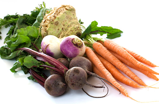 Organic carrots, beets, turnips, and celery root on a white background