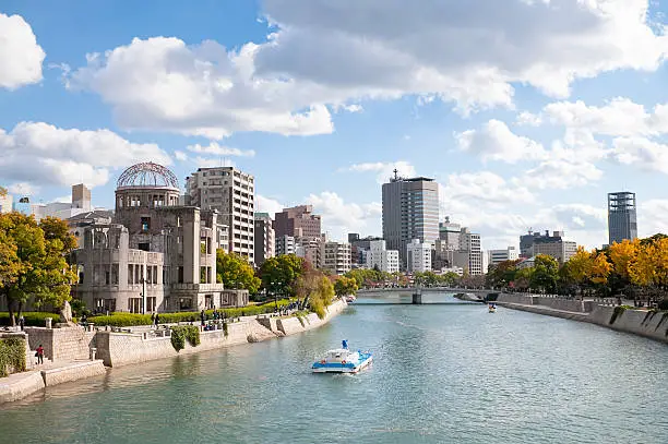 Autumn colours along the banks of the Ota River in central Hiroshima.  To the left is the UNESCO protected Atomic Bomb Dome building, which was close to the detonation site of the nuclear bomb that fell on 6th August 1945.   The building has been intentionally left in an unrepaired state since 1945.