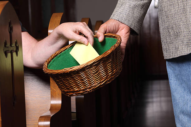 Woman Tithing Woman's hand putting an envelope in the collection basket at church religious offering stock pictures, royalty-free photos & images