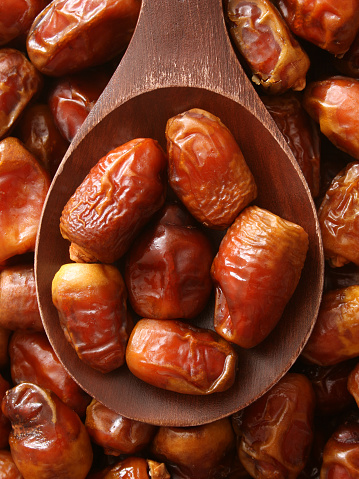 Top view of wooden spoon full of dates