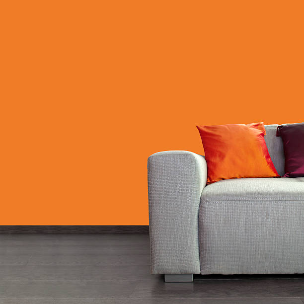 istock Modern gray sofa and colorful pillows against orange wall 157530637