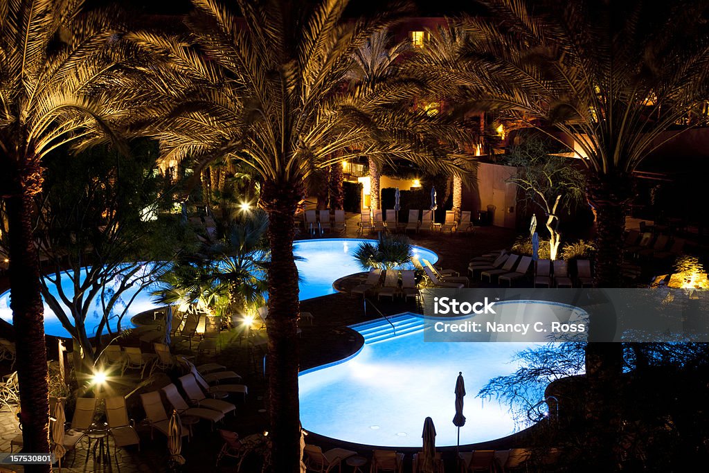 Бассейны курорта ночью с изображением пальмовых деревьев - Стоковые фото Бассейн на курорте роялти-фри
