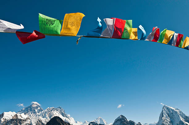 Mt Everest summit vibrant buddhist prayer flags flying blue sky Brightly colored Buddhist prayer flags flying in a deep blue high altitude sky over the iconic pyramid peak of Mt. Everest and the snow capped summits of Nuptse, Lhotse and the Western Cwm high in the remote Himalaya of Nepal. ProPhoto RGB profile for maximum color fidelity and gamut. nepal stock pictures, royalty-free photos & images