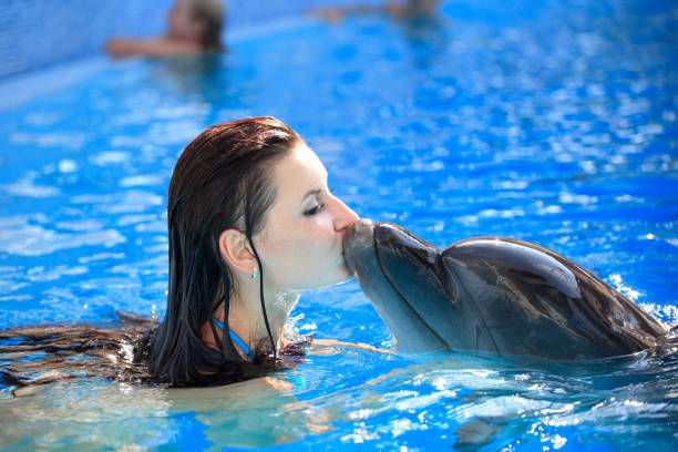 young woman kissing a dolphin