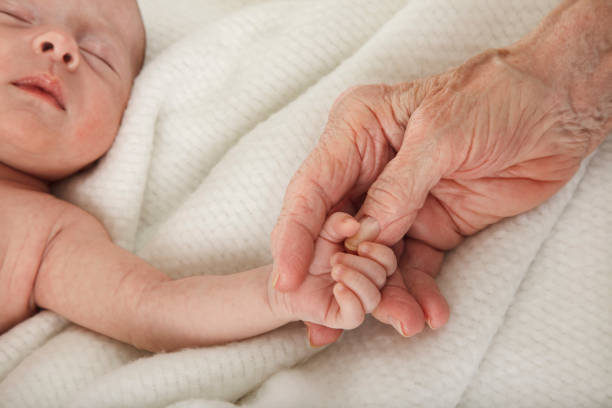 dormire il bambino tenendo la mano di grande nonna - baby grandparent newborn grandmother foto e immagini stock