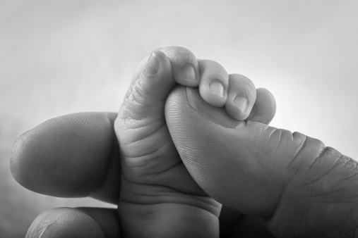 One-month-old baby girl sleeping while holding her father’s hand, photo, white background