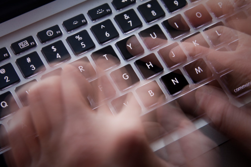Hands typing on laptop keyboard - Motion blur.