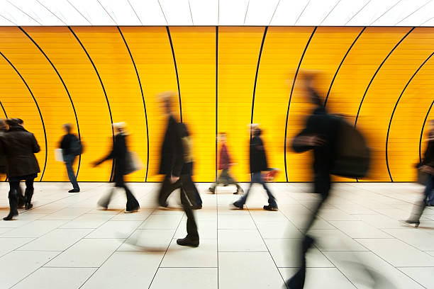 people blurry in motion in yellow tunnel down hallway - klant fotos stockfoto's en -beelden
