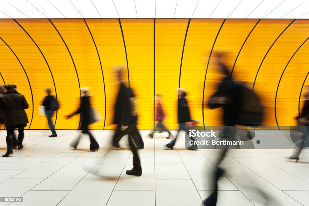 People blurry in motion in yellow tunnel down hallway blurred and defocused people walking People Stock Photo