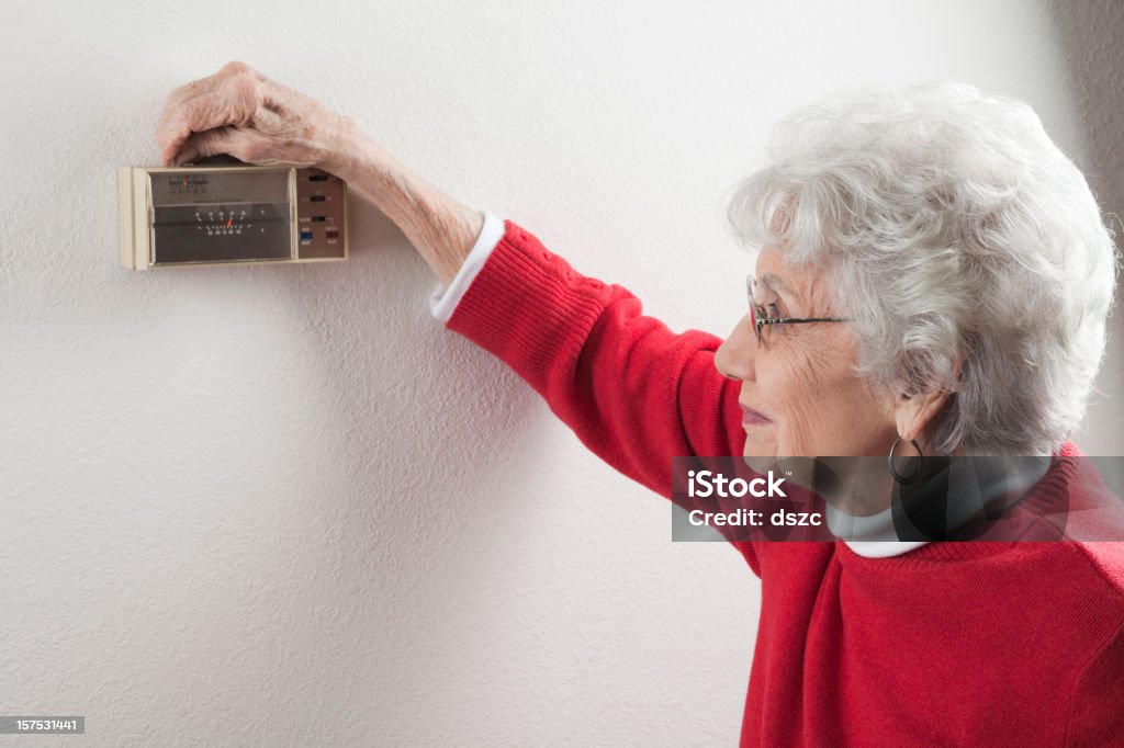 Sênior mulher, ajustando casa o termostato - Foto de stock de Termostato royalty-free