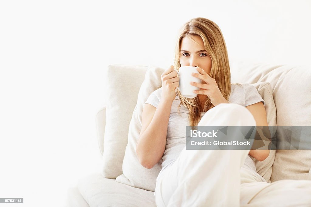 Attraente giovane donna bere il caffè nel divano - Foto stock royalty-free di Modella