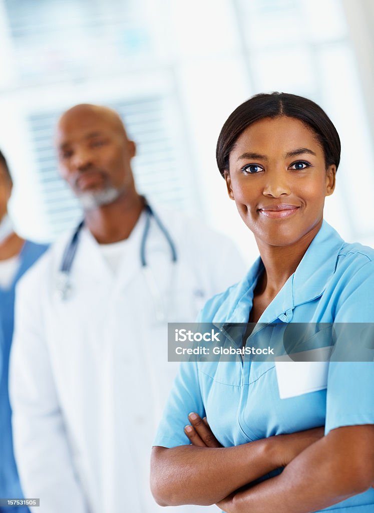 アフリカ系アメリカ人の看護師笑顔で、お仕事仲間との背景 - 1人のロイヤリティフリーストックフォト