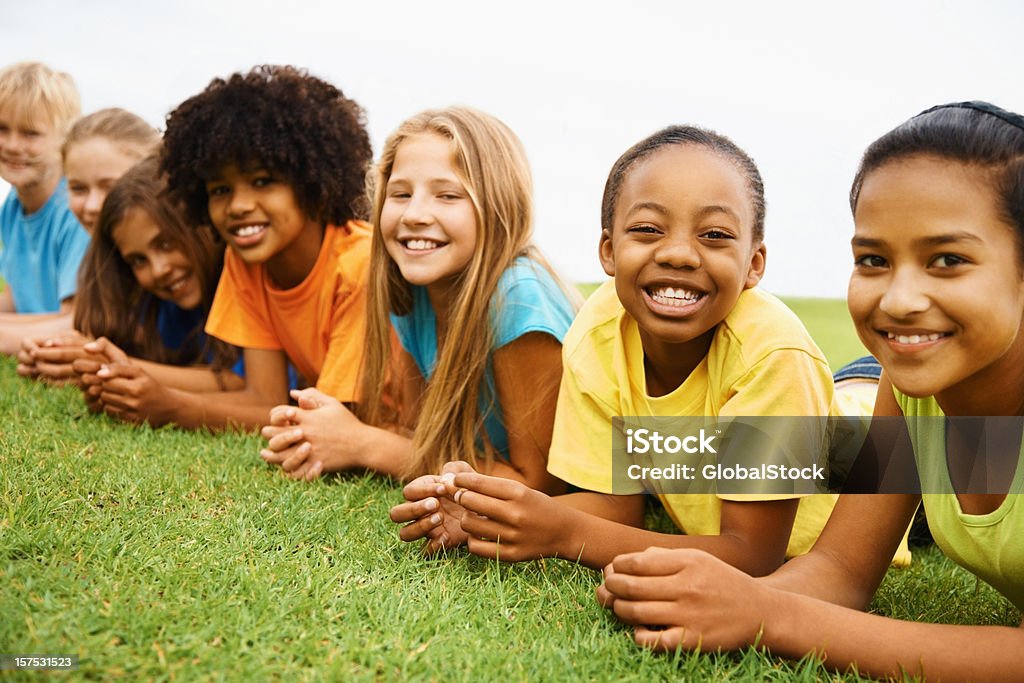 Feliz multi étnica niños lying on grass - Foto de stock de 10-11 años libre de derechos