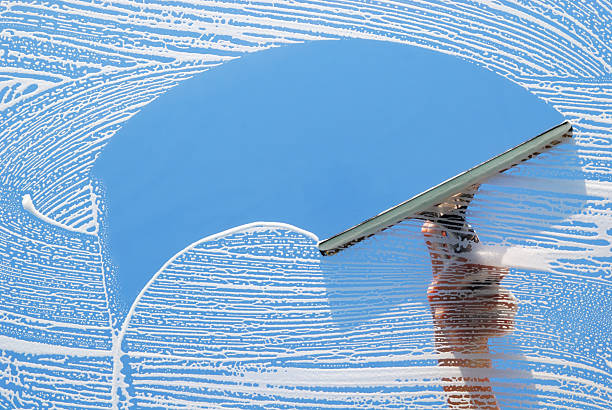 Domestic Window Cleaner washing a window with a squeegee.