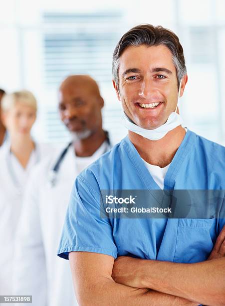 Foto de Médico Masculino Sorrindo Com Colegas No Fundo e mais fotos de stock de 30 Anos - 30 Anos, 35-39 Anos, Adulto