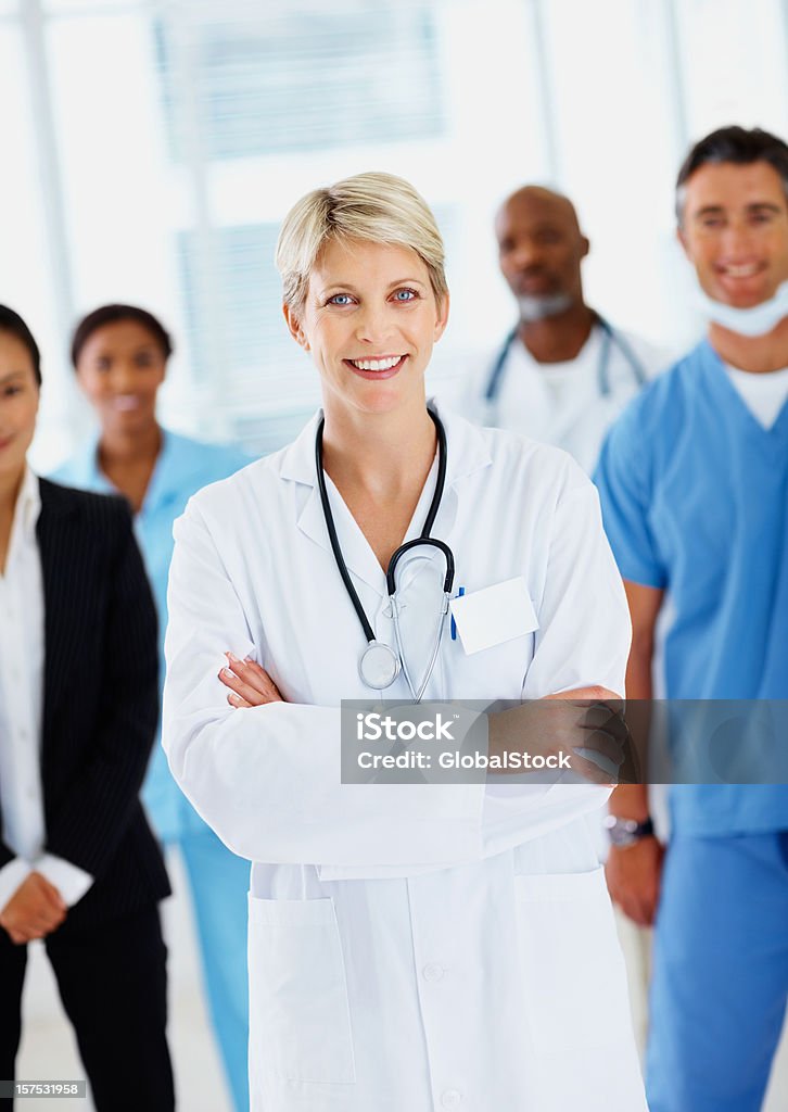 Женский доктор, улыбается с коллегами в фоновом режиме - Стоковые фото 20-24 года роялти-фри