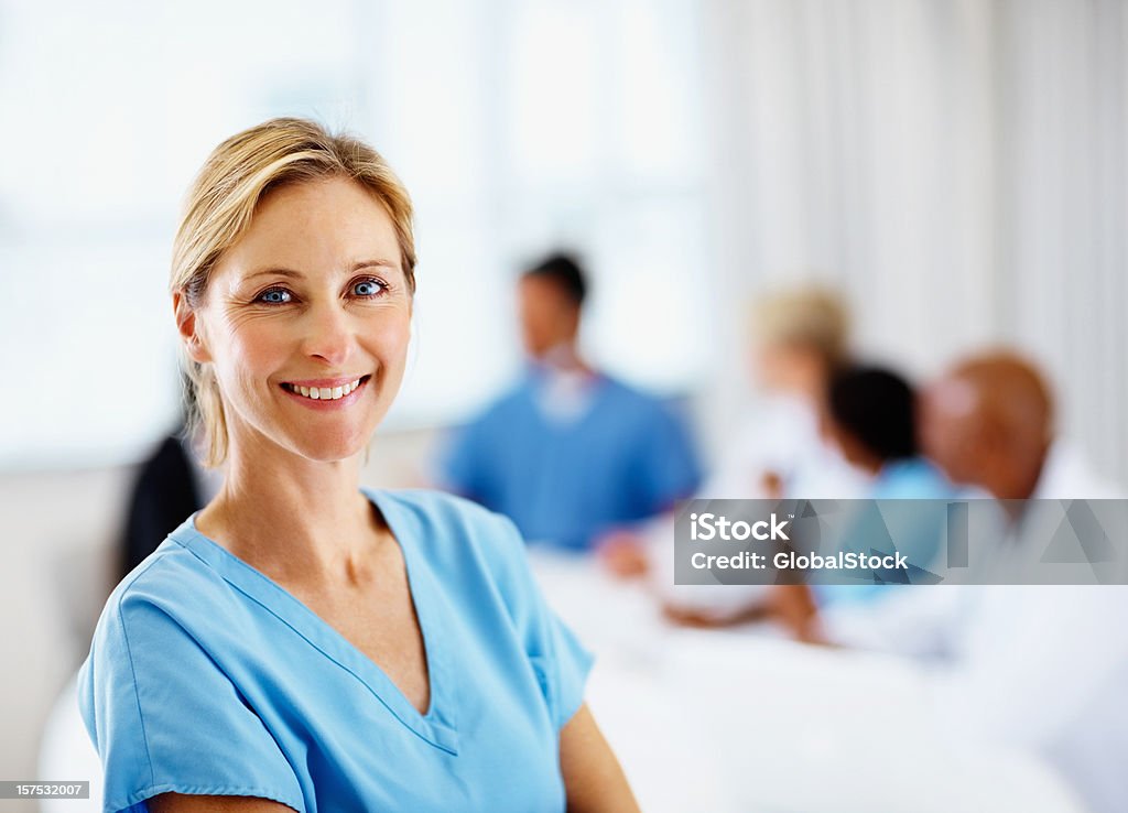 Kobieta Chirurg uśmiechając się z kolegami na plecach - Zbiór zdjęć royalty-free (Blond włosy)