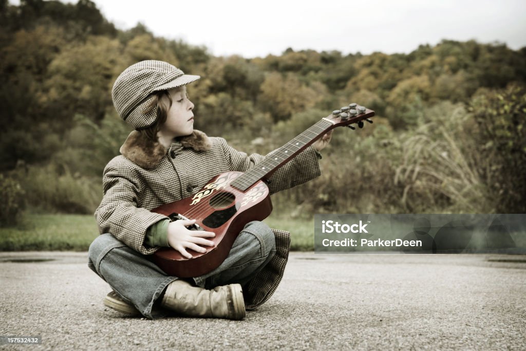 Encantadores Little Boy Playing Guitar en Prairie - Foto de stock de Agarrar libre de derechos