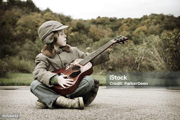Encantadores Little Boy Playing Guitar En Prairie Foto de stock y más banco de imágenes de Agarrar - Agarrar, Aire libre, Alegre