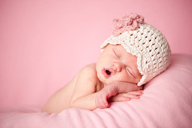 Sleeping Newborn Baby Girl Wearing a Crocheted Hat on Pink stock photo
