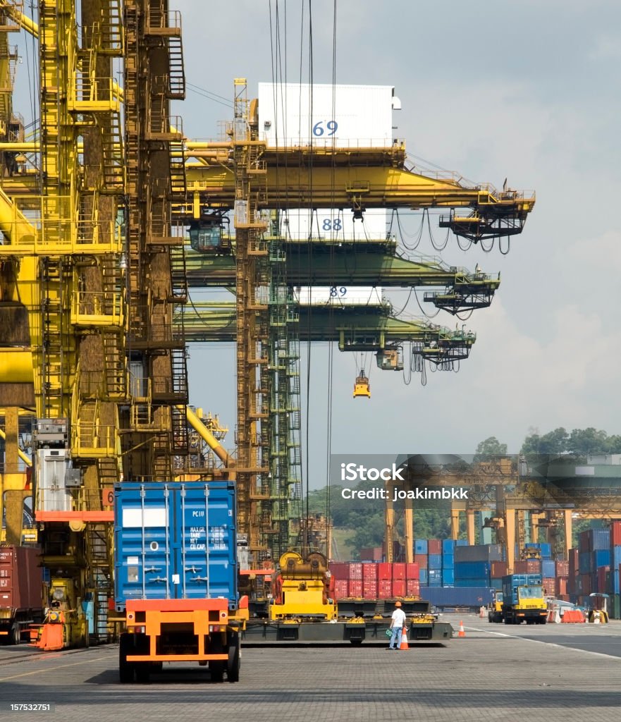 Industrial crane in the nusy harbor of Singapore Downloading and uploading containers on trucks in the harbor of Singapore. All trademarks were carefully removed. Further choice below: Asia Stock Photo