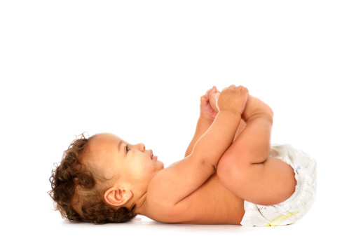A biracial baby lying down holding his feet isolated on white