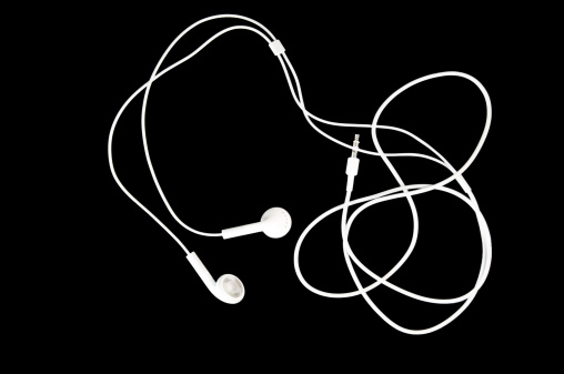 Brilliant white earbuds on a black background with copy space.