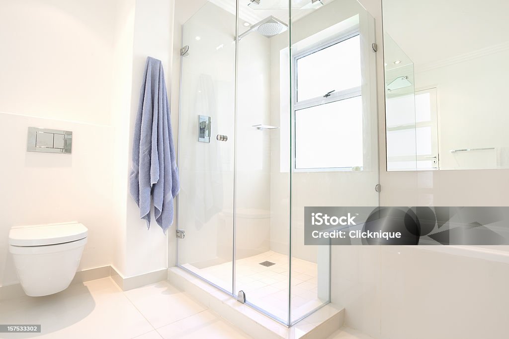 Modern upmarket domestic bathroom An all white bathroom showing the bath, shower and toilet with dual flush. Bathroom Stock Photo