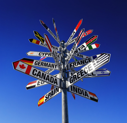Low-angle view of signpost showing states of the world and their flags.