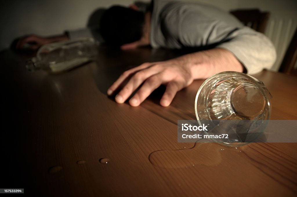 Алкоголь Злоупотребляют концепция человек лежал на сто�ле в нетрезвом состоянии - Стоковые фото Токсичное вещество роялти-фри