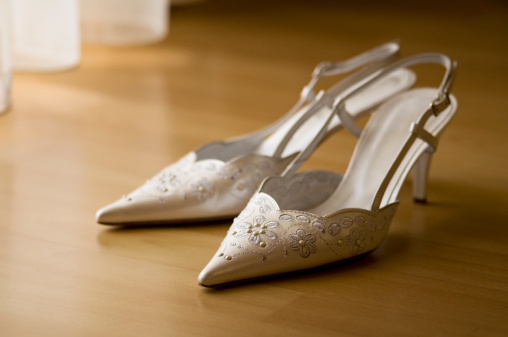 Deail of Luxury Bride's shoes on brown parquet.