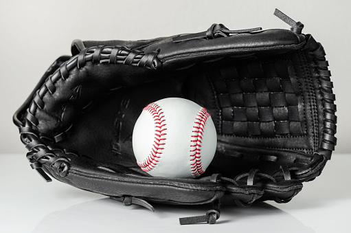 A dark colored fastpitch softball catchers mitt with a yellow softball in the webbing.