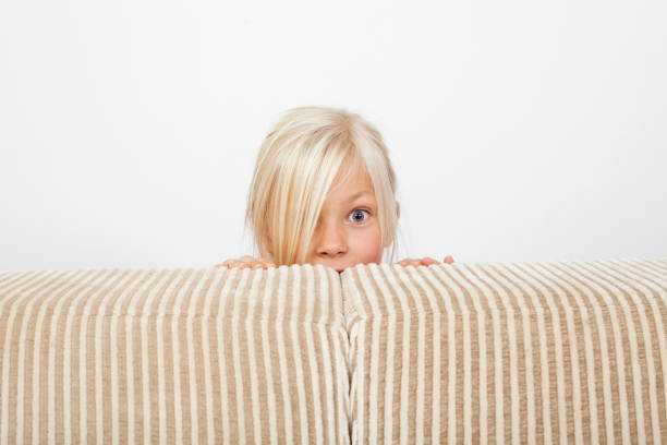 istock Happy girl behinde sofa making a face 157534031
