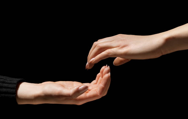 istock Two Hands Reach Out In Darkness to Hold, Help One-Another 157534102