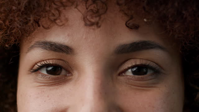 Half Female Face Looking At Camera. Black woman eyes opening at camera. Slow motion, close up.