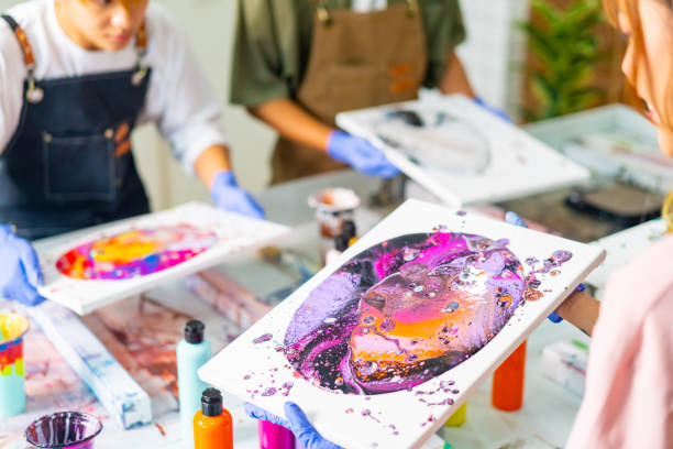 Group of Young Asian people learning acrylic pouring art at art studio. Group of Asian generation z people learning acrylic pouring art on canvas workshop at art studio. Young artist university student enjoy and fun creating design colorful abstract modern art in class. abstract oil painting for beginners stock pictures, royalty-free photos & images