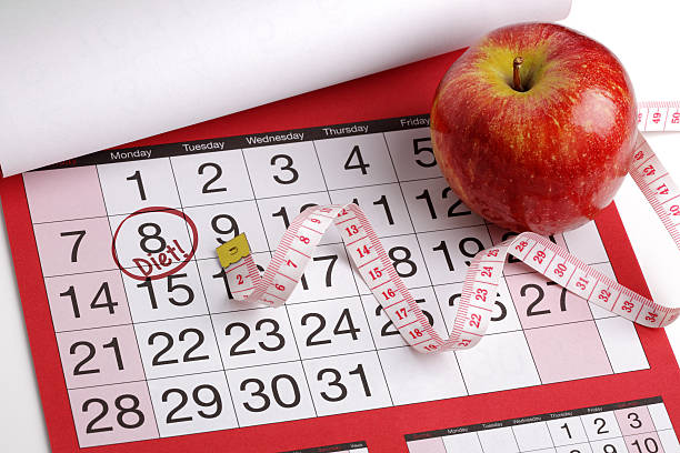 Health plan with notebook and pencil on wooden table with apple and tape measure. Top view.