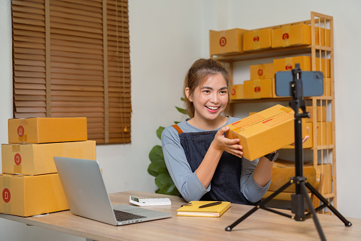 Young woman working online e-commerce shopping at her shop doing live streaming.