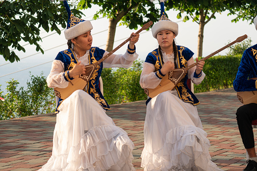 Kazakh woman in blue costume playing dombra Kazakh musical instrument , Almaty, Kazakhstan. May 25, 2023