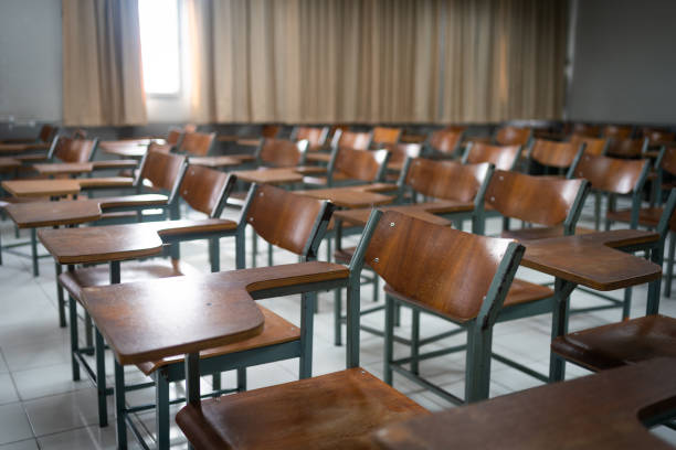 istock Empty classroom with vintage tone wooden chairs. Back to school concept 1575498664