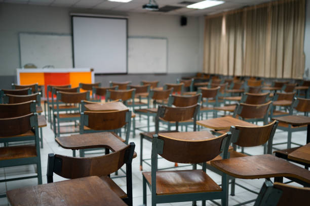istock Empty classroom with vintage tone wooden chairs. Back to school concept 1575498683
