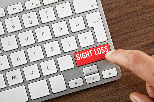 Man pushing ”Sight loss” key on computer keyboard.
