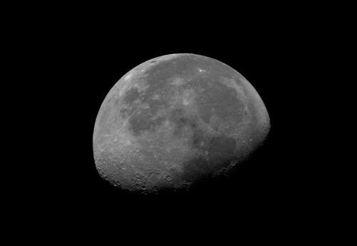 Photo of half of the big moon on its side with craters and seas. Satellite of the Earth in the phase of the first quarter. The science of astronomy and astrophotography through a telescope